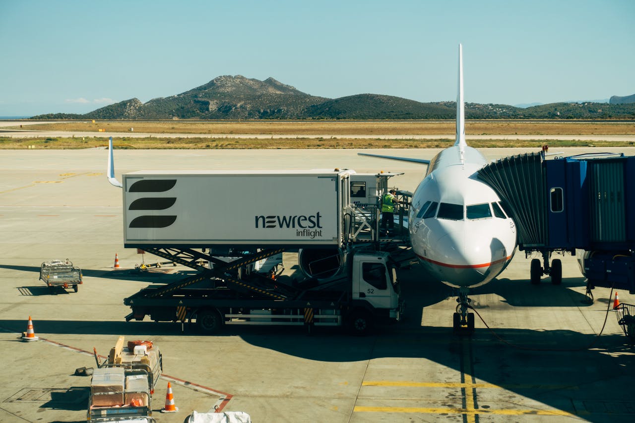A commercial airplane being serviced at an airport with fueling and loading equipment.